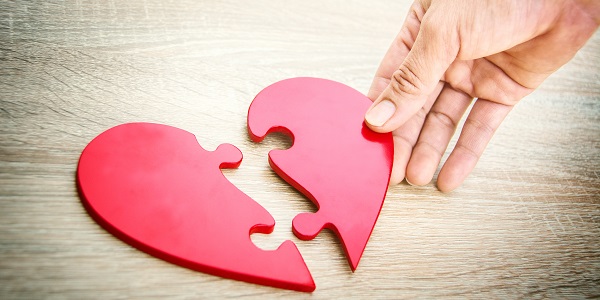 Female,Hand,Matching,Red,Jigsaw,Heart,Halves,On,Grey,Wooden